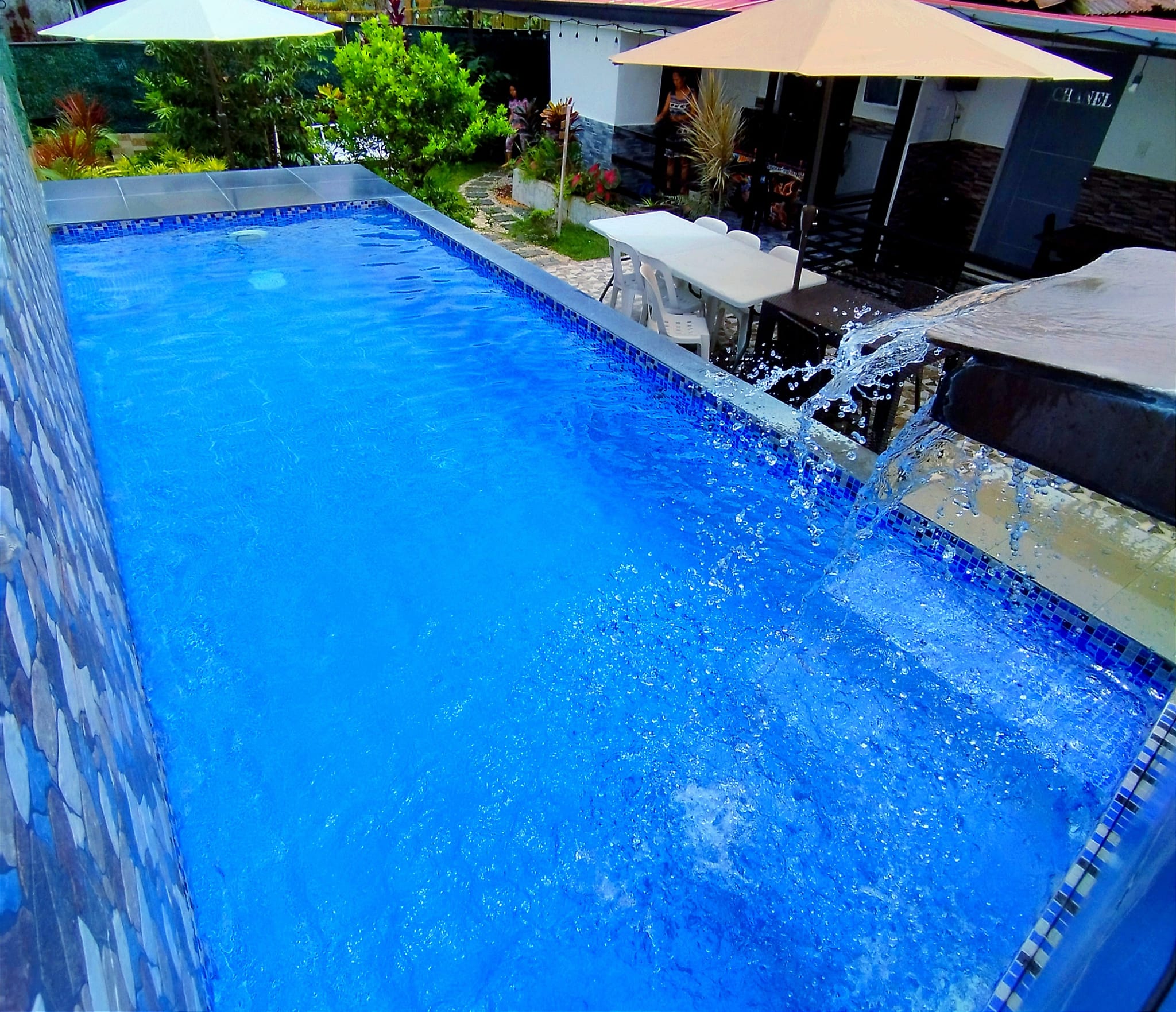 Private pool with cascading water feature and umbrellas