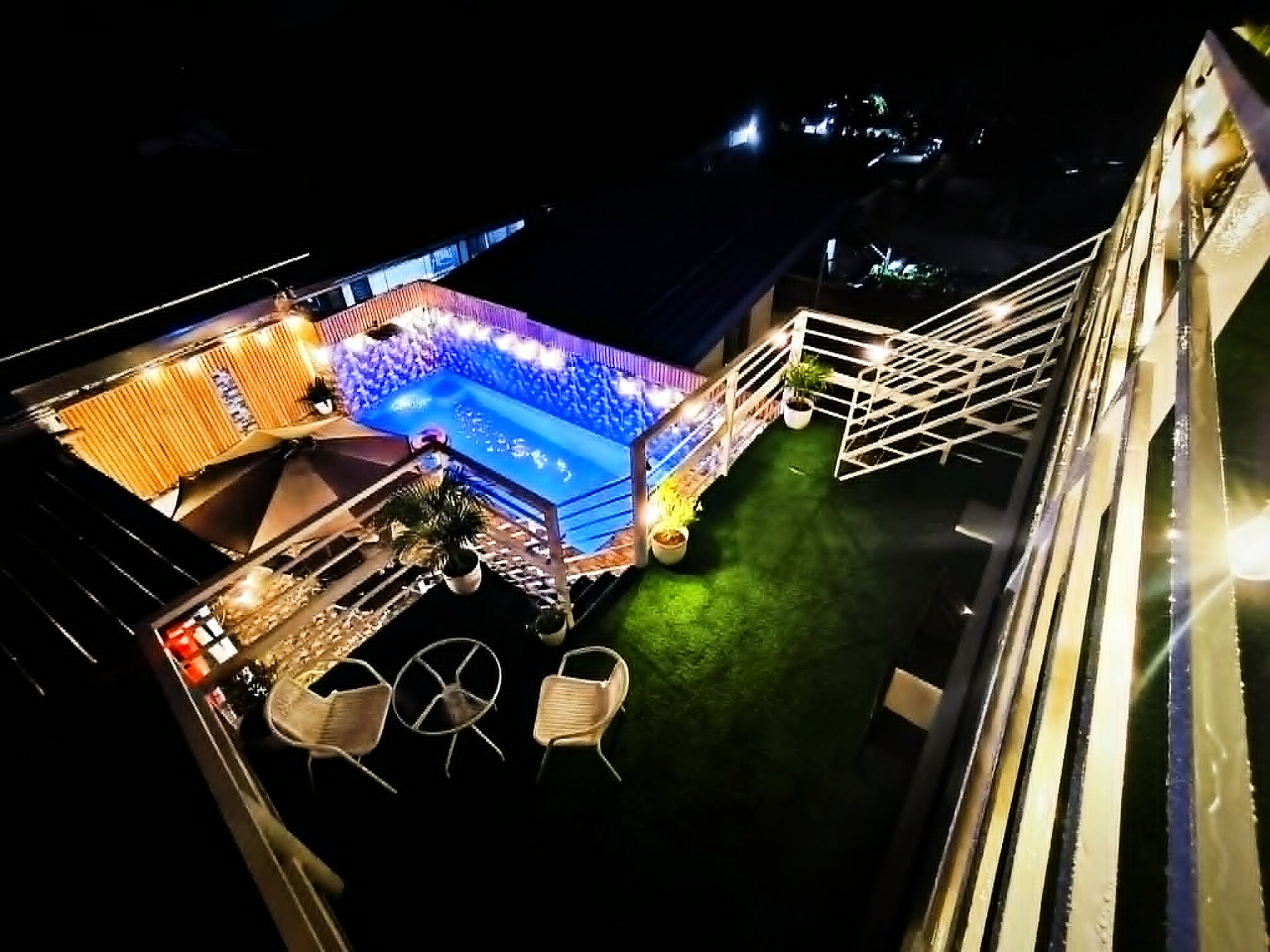 Aerial view of the illuminated pool and outdoor lounge at night