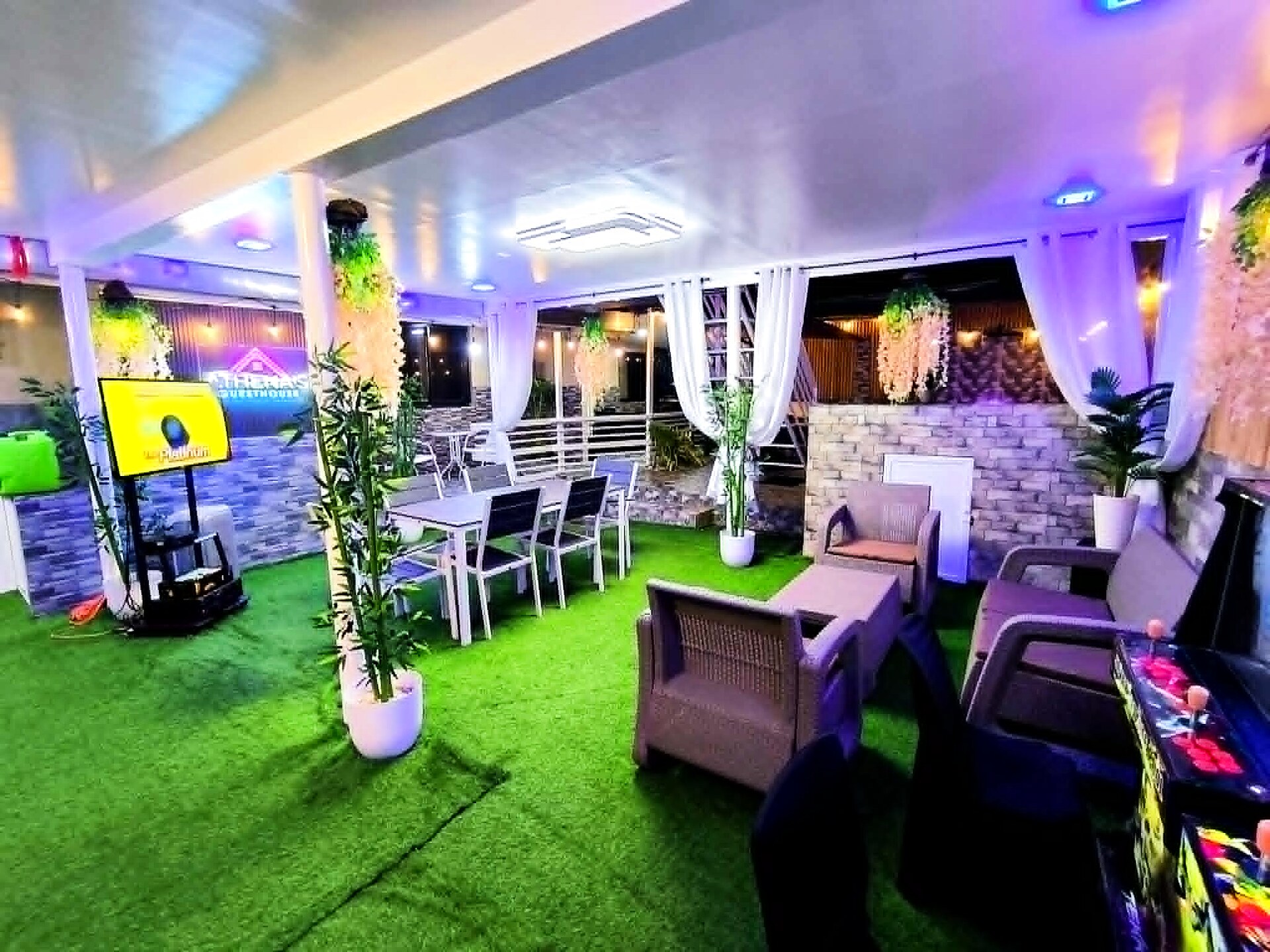 Indoor lounge with karaoke setup, dining, and ambient lighting