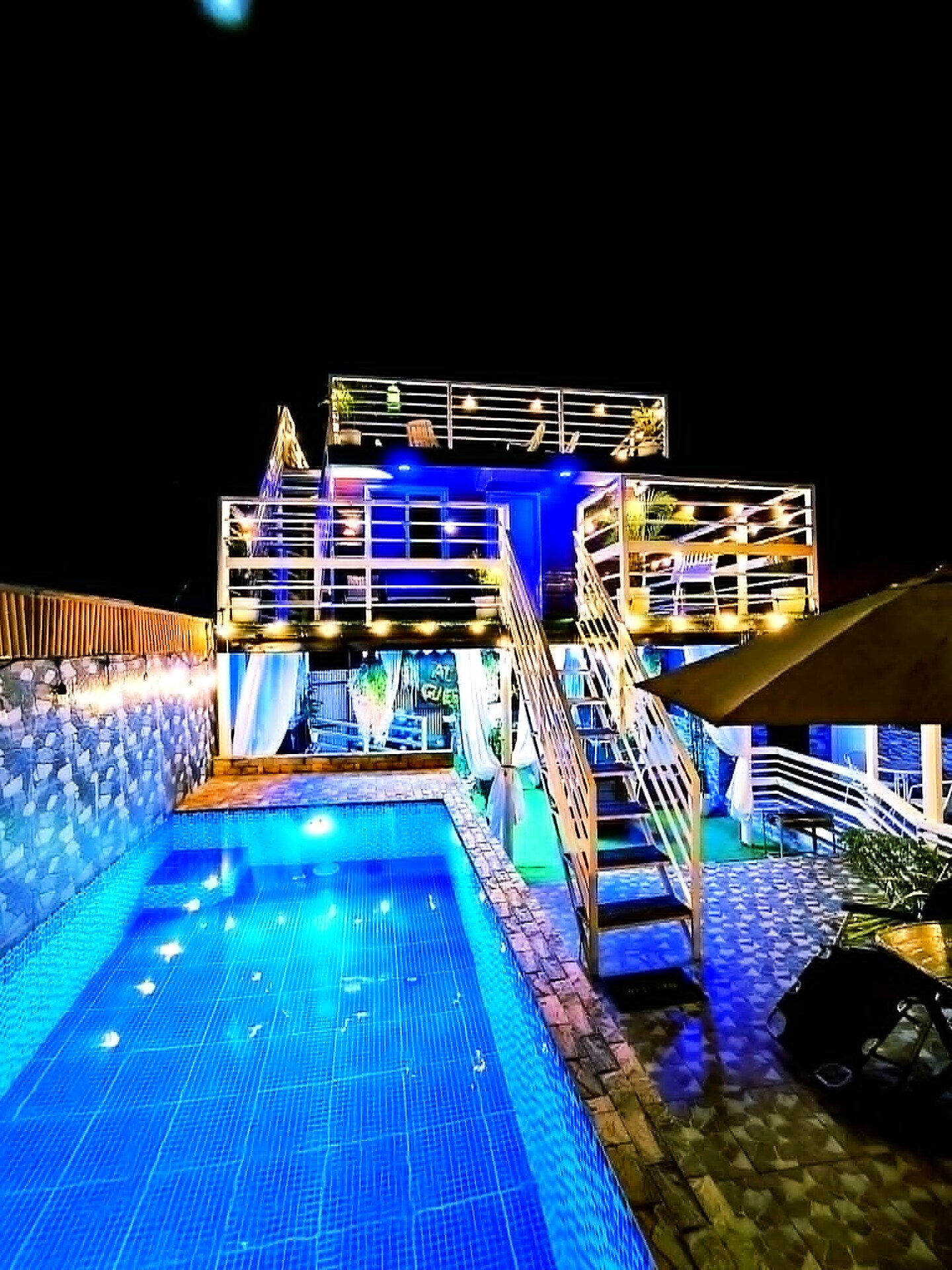 Glowing pool at night framed by the multi-level guesthouse
