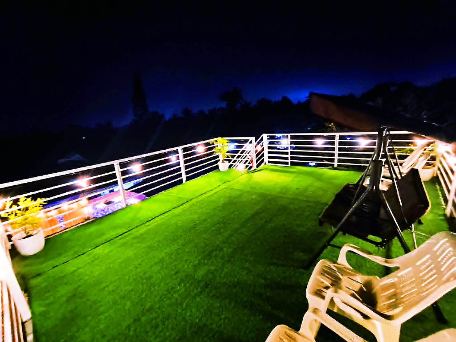 Rooftop deck with artificial grass and string lights at night